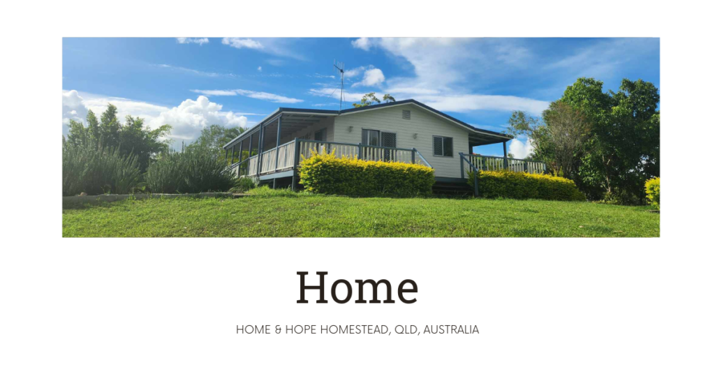 Home and Hope white weatherboard Queenslander house on top of a lush gren hill